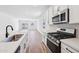 Modern kitchen features stainless appliances, a sleek sink, and stylish white cabinetry, creating a contemporary cooking space at 47771 W Mellen Ln, Maricopa, AZ 85139