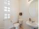 Clean and simple bathroom with pedestal sink, toilet, and block windows at 11453 E Mark Ln, Scottsdale, AZ 85262