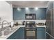 Modern kitchen with stainless steel appliances and dark teal cabinets at 16 W Encanto Blvd # 409, Phoenix, AZ 85003