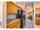 Kitchen features wood cabinets, black appliances, and a view into the dining area at 6751 N 77Th Dr, Glendale, AZ 85303