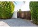 Wooden gate entrance with gravel driveway and lush landscaping at 8431 E Stella Ln, Scottsdale, AZ 85250