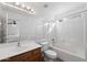 Bright bathroom with white tiling around the bathtub and shower and a wood vanity with a large mirror at 8549 E Carol Ave, Mesa, AZ 85208