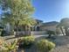 House with a large tree, desert landscaping, and stone accents at 15583 W Big Sky Dr, Surprise, AZ 85374