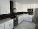 Modern kitchen with white cabinets, geometric backsplash and a black range hood at 4016 W Wagon Wheel Dr, Phoenix, AZ 85051