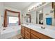 Bathroom with double sinks, a soaking tub, and wood vanity at 10642 W Mohawk Ln, Peoria, AZ 85382