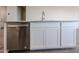 Kitchen island with stainless steel dishwasher, white cabinets, granite countertop, and sink at 24636 W Hopi St, Buckeye, AZ 85326