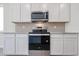 Close-up of the kitchen featuring stainless steel oven, microwave, white cabinets and tile backsplash at 24636 W Hopi St, Buckeye, AZ 85326