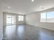 Open-concept living room with gray tile flooring, large windows, and sliding glass doors at 24636 W Hopi St, Buckeye, AZ 85326