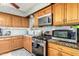 View of kitchen with wood cabinets, gas stove, microwave, and granite countertop at 2825 N 33Rd Pl, Phoenix, AZ 85008