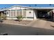 Single-wide manufactured home with carport and desert landscaping at 9302 E Broadway Rd # 103, Mesa, AZ 85208