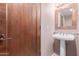Elegant powder room with pedestal sink and rich wood door at 36601 N Mule Train Rd # B19, Carefree, AZ 85377