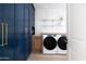 Laundry room with modern washer, dryer, and blue cabinetry at 6140 E Calle Tuberia --, Scottsdale, AZ 85251