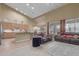 Open-concept living room featuring neutral decor, vaulted ceiling, kitchen, and ample natural light from large windows at 6216 W Morrow Dr, Glendale, AZ 85308