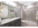 Bathroom featuring a granite countertop vanity and tiled walk-in shower with glass door at 18404 W Long Lake Rd, Goodyear, AZ 85338