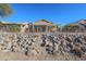 Home's exterior back view with a large stone retaining wall at 19778 N Coyote Lakes Pkwy, Surprise, AZ 85378