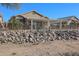 Backyard view of home with large stone retaining wall at 19778 N Coyote Lakes Pkwy, Surprise, AZ 85378