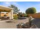 Relaxing backyard oasis with covered patio, seating area, and mature plants at 21295 N 262Nd Dr, Buckeye, AZ 85396