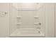 Bright white bathtub and shower combination, showcasing clean lines, shelves, and modern fixtures at 22541 W Pontiac Dr, Surprise, AZ 85387