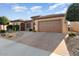 Tan colored house with a brown door and garage doors, plus a nicely landscaped yard at 26783 W Piute Ave, Buckeye, AZ 85396