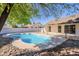 Blue kidney-shaped pool with rocks and a tree at 7101 W Laurel Ln, Peoria, AZ 85345