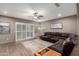 Spacious living room featuring hardwood floors, sliding glass doors, and a comfortable leather sectional sofa at 17482 W Pinnacle Vista Dr, Surprise, AZ 85387