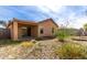 A view of the covered patio and desert-landscaped backyard with sliding glass doors to the home at 2716 W Allens Peak Dr, San Tan Valley, AZ 85144