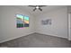 Well-lit bedroom with grey carpet, window, and ceiling fan at 16871 W Cielo Grande Ave, Surprise, AZ 85387