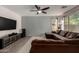 Living room with hardwood floors, brown sectional couch and large TV at 3496 E Anika Ct, Gilbert, AZ 85298