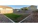 Landscaped backyard with grassy area and rock border at 40561 W Hillman Dr, Maricopa, AZ 85138