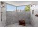 Shower featuring neutral-colored tiles, a wooden bench, and picturesque mountain views from the window at 5655 N Camelback Canyon Dr, Phoenix, AZ 85018