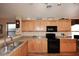 Bright kitchen with oak cabinets, granite countertops, and black appliances at 6808 S 36Th Dr, Phoenix, AZ 85041