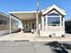 Tan mobile home with covered patio, landscaping, and a paved driveway at 840 S Aquamarine Dr, Apache Junction, AZ 85119