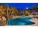 Stunning nighttime view of a luxurious pool with waterfall feature and mountain backdrop at 10756 E Ludlow Dr, Scottsdale, AZ 85255