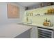 Modern wet bar with white cabinets, quartz countertop, and wine cooler at 10758 E Tamarisk Way, Scottsdale, AZ 85262