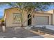 Tan house with a large tree and gravel landscaping at 16955 W Holly St, Goodyear, AZ 85395