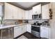 White kitchen cabinets, granite counters, and stainless steel appliances at 1908 E Hawken Pl, Chandler, AZ 85286