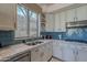 Bright kitchen features stainless steel appliances, granite counters, white cabinetry, and a view of the backyard at 2418 E Glass Ln, Phoenix, AZ 85042