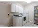 Functional laundry room with modern washer and dryer units, storage cabinets, and plenty of space at 2418 E Glass Ln, Phoenix, AZ 85042