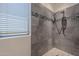 Close up of shower with mosaic detail and pebble floor, plus a large window for natural light at 2418 E Glass Ln, Phoenix, AZ 85042