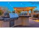 Built-in outdoor kitchen with grill, stone countertops, and string lights at 32029 N 19Th Ln, Phoenix, AZ 85085