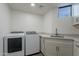 Bright laundry room featuring modern washer and dryer, granite countertop, and stainless steel sink at 39493 N 107Th Way, Scottsdale, AZ 85262