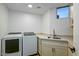 Well-lit laundry room with white cabinets, sink, and modern washer and dryer at 39493 N 107Th Way, Scottsdale, AZ 85262