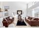 Spacious living room with two brown leather sofas, a coffee table, and large windows at 5748 W Soft Wind Dr, Glendale, AZ 85310