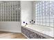 Elegant bathroom featuring a large soaking tub, glass block window, and mosaic tile accents at 1104 N Oak Ct, Gilbert, AZ 85233