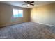 Spacious carpeted bedroom with a window and ceiling fan at 13943 S Amado Blvd, Arizona City, AZ 85123