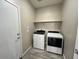 Convenient laundry room with modern washer, dryer, and storage shelf at 17066 W Seldon Ln, Waddell, AZ 85355