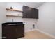 Modern laundry room with dark cabinetry, quartz countertops, and wood shelving at 25838 N 104Th Pl, Scottsdale, AZ 85255