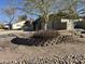 Landscaped front yard with desert rock, a mature tree, and a charming retaining wall with a flowering bush at 511 E Port Au Prince Ln, Phoenix, AZ 85022