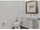 Neat half bathroom with a pedestal sink, modern mirror, and stylish fixtures offers convenience for guests at 55 N Abalone Ct, Gilbert, AZ 85233