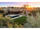 Luxury home with a pool and grassy backyard, palm trees and sunset in background at 6708 E Calle De Las Estrellas Rd, Cave Creek, AZ 85331